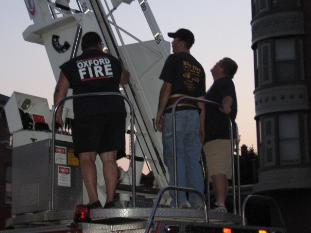 Donald Slauch operates the ladder while Morgan Derr prepares to climb and Bill Goodley watches.